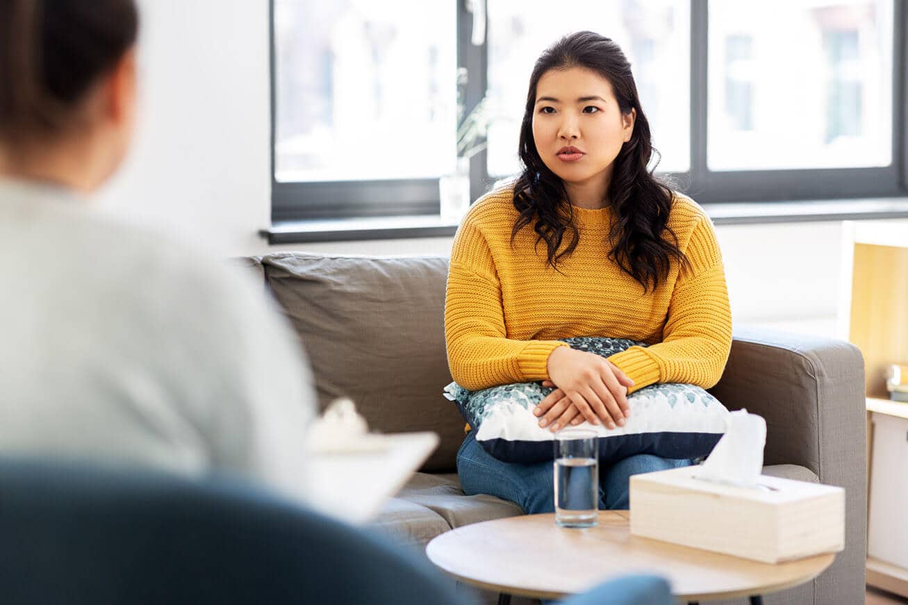 Shot of a young woman wearing a yellow sweater having a therapeutic session with a psychologist