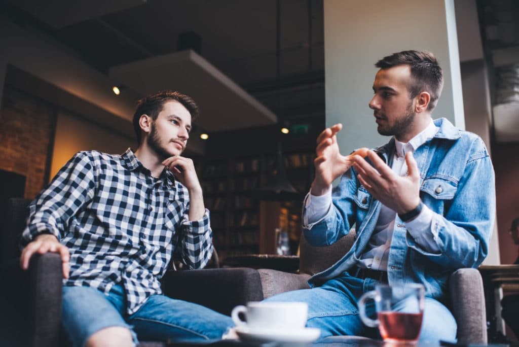 Two male friends having coffee and talking.