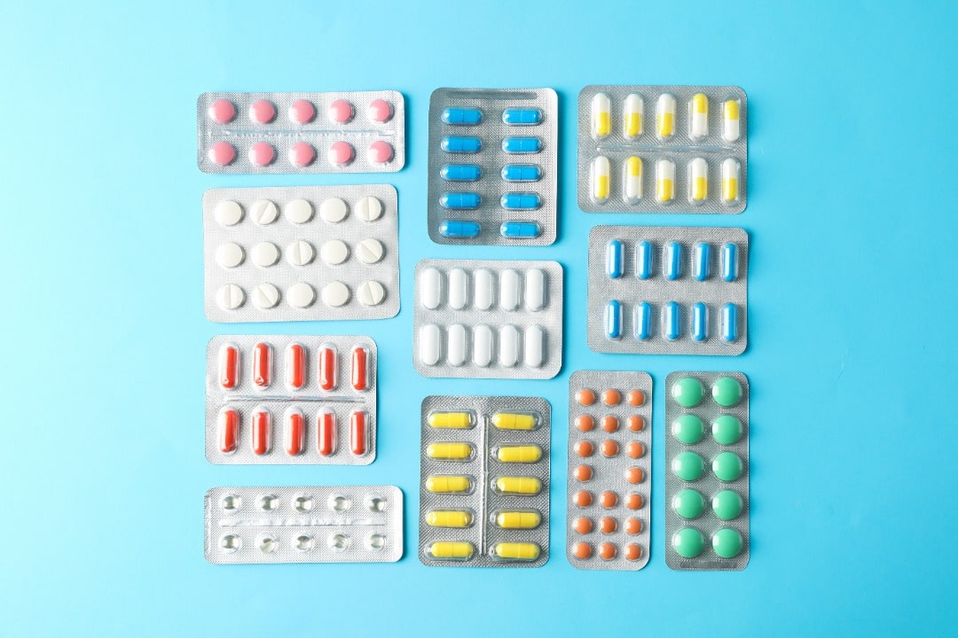 Several types of blister packets of meds arranged on a blue background.